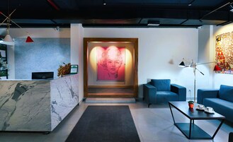 Una zona de recepción moderna con mostrador de mármol, pantalla digital y una gran obra de arte abstracta.