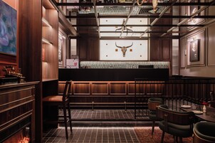 Una zona de bar con paneles de madera, un adorno en la pared con un cráneo de toro y un salpicadero de azulejos.
