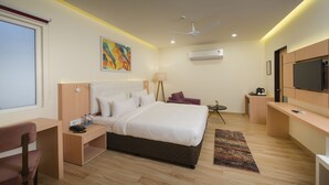 Une chambre d’hôtel moderne équipée d’un grand lit, d’un bureau, d’une chaise, d’une télévision et d’un ventilateur de plafond.