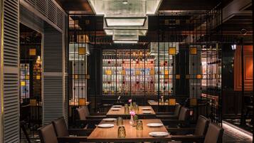 A restaurant interior with a long dining table, chairs, and a modern chandelier.