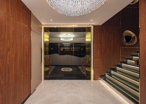 L'entrée d'un hôtel au design moderne, avec un imposant lustre, un escalier et un espace d'accueil.