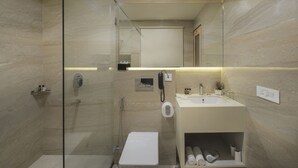Une salle de bain moderne dotée d’une douche à parois de verre, de toilettes, d’un lavabo et d’un miroir.