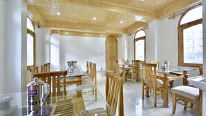 A spacious dining area with wooden furniture and large windows. - OYO 12271 Avenue Manali (Manali)