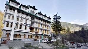 A multi-story hotel with balconies, a sign reading "Avenue Manali," and a mountainous backdrop. - OYO 12271 Avenue Manali (Manali)