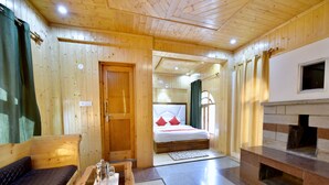 A wooden cabin interior with a bed, a fireplace, a seating area, and a small table with a tray. - OYO 12271 Avenue Manali (Manali)
