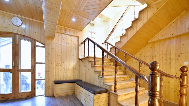A wooden interior with a staircase, a bench, and a clock on the wall. - OYO 12271 Avenue Manali (Manali)