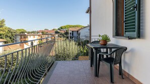 A balcony with a view of buildings and greenery, a table with chairs, and a potted plant. - I Pungenti (Rosignano Marittimo)