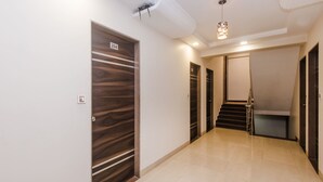A modern hallway with a wooden door labeled "204," a staircase, and a ceiling-mounted light fixture. - OYO 3551 Hotel Elite Inn (Navi Mumbai)