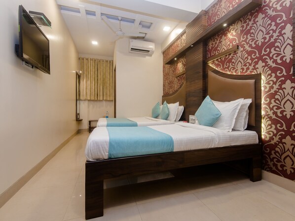 A hotel room with a large bed, a flat-screen TV mounted on the wall, and a ceiling fan.