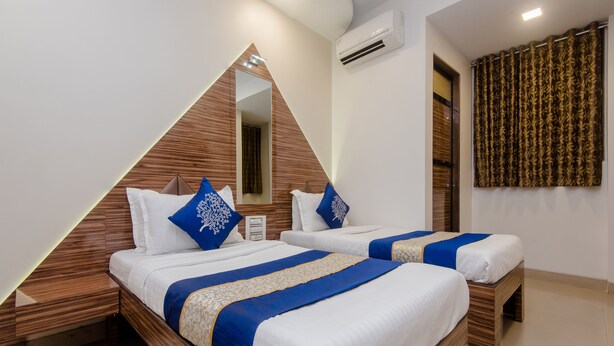 A modern hotel room with two beds, wooden headboards, and a large mirror. - OYO 3551 Hotel Elite Inn (Navi Mumbai)