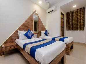 Ein modernes Hotelzimmer mit zwei Betten, Holz-Kopfteilen und einem großen Spiegel.