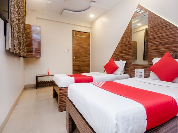 A hotel room with two beds, wooden headboards, a small bedside table, and a mirror.