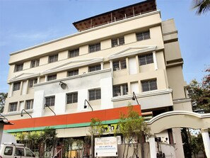 A multi-story building with a flat facade, multiple windows with metal bars, and a signboard at the ground level. - OYO 10678 Hotel Nandanvan (Pune)