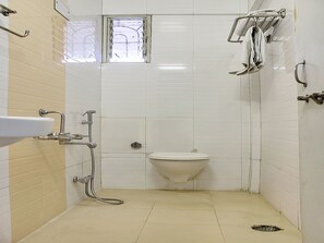 A small, basic bathroom with a toilet, a sink, and a shower area. - OYO 10678 Hotel Nandanvan (Pune)