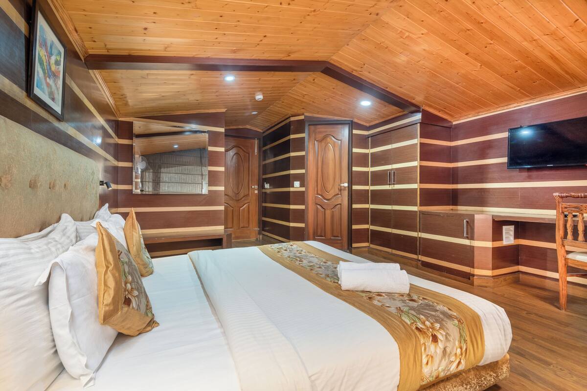 Ein Zimmer mit Holzvertäfelung, einem Bett, einem Fernseher und einem Kleiderschrank.