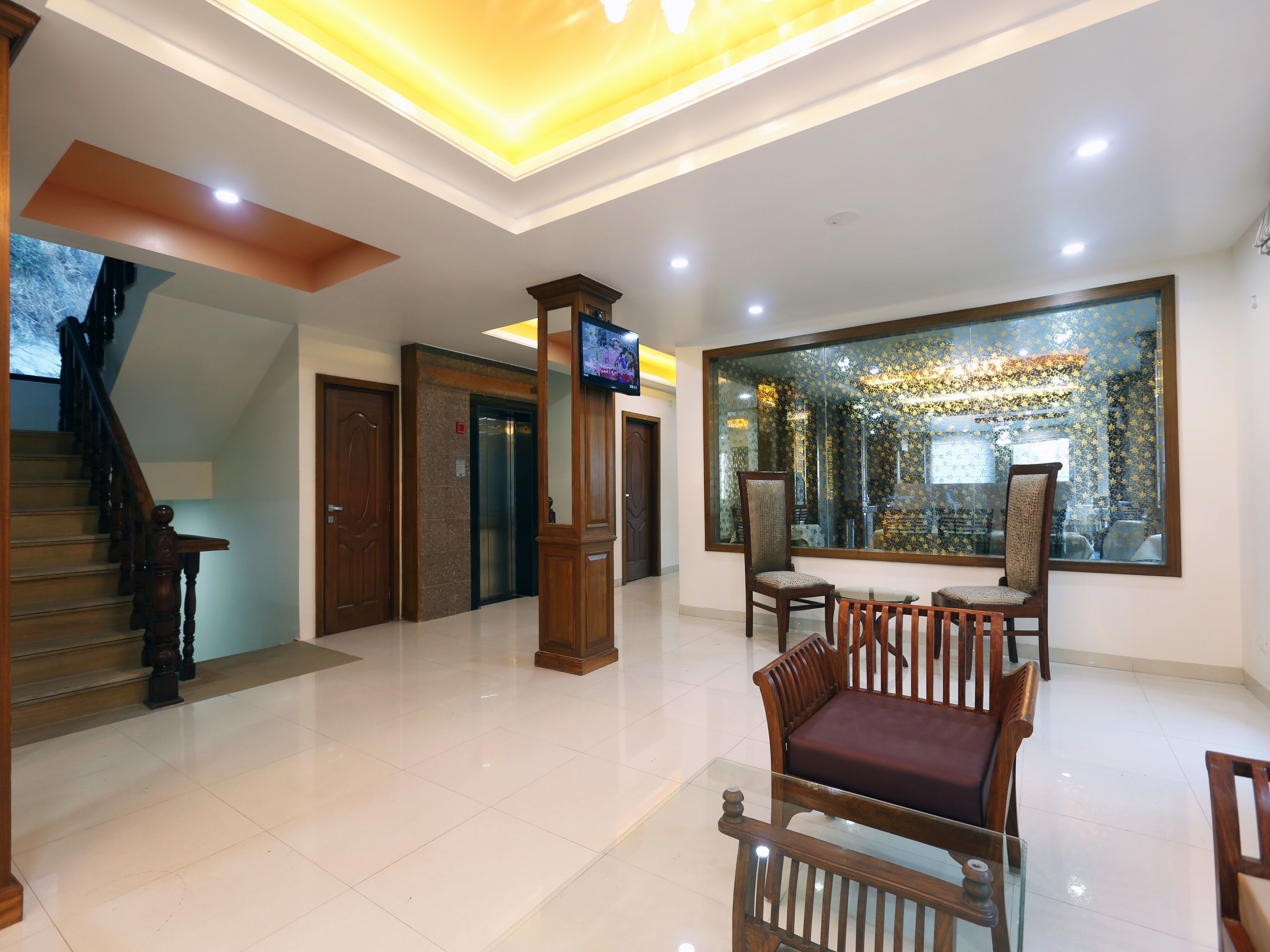 A spacious lobby with a wooden staircase, a reception desk, and a large decorative window.