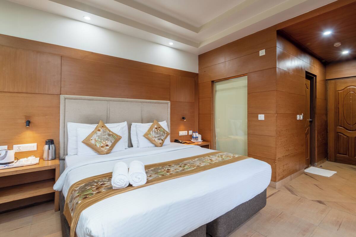 Ein Hotelzimmer mit einem großen Bett, holzverkleideten Wänden, einer Holztür und einem Nachttisch mit Lampe und Telefon.