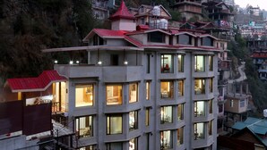 Un hôtel à plusieurs étages, doté de balcons, de grandes fenêtres et d’un toit rouge.