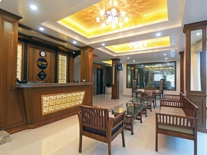 A hotel lobby with a reception desk, wooden chairs, a glass table, and a chandelier. - Hotel The Rock Castle by DLS Hotels (Shimla)