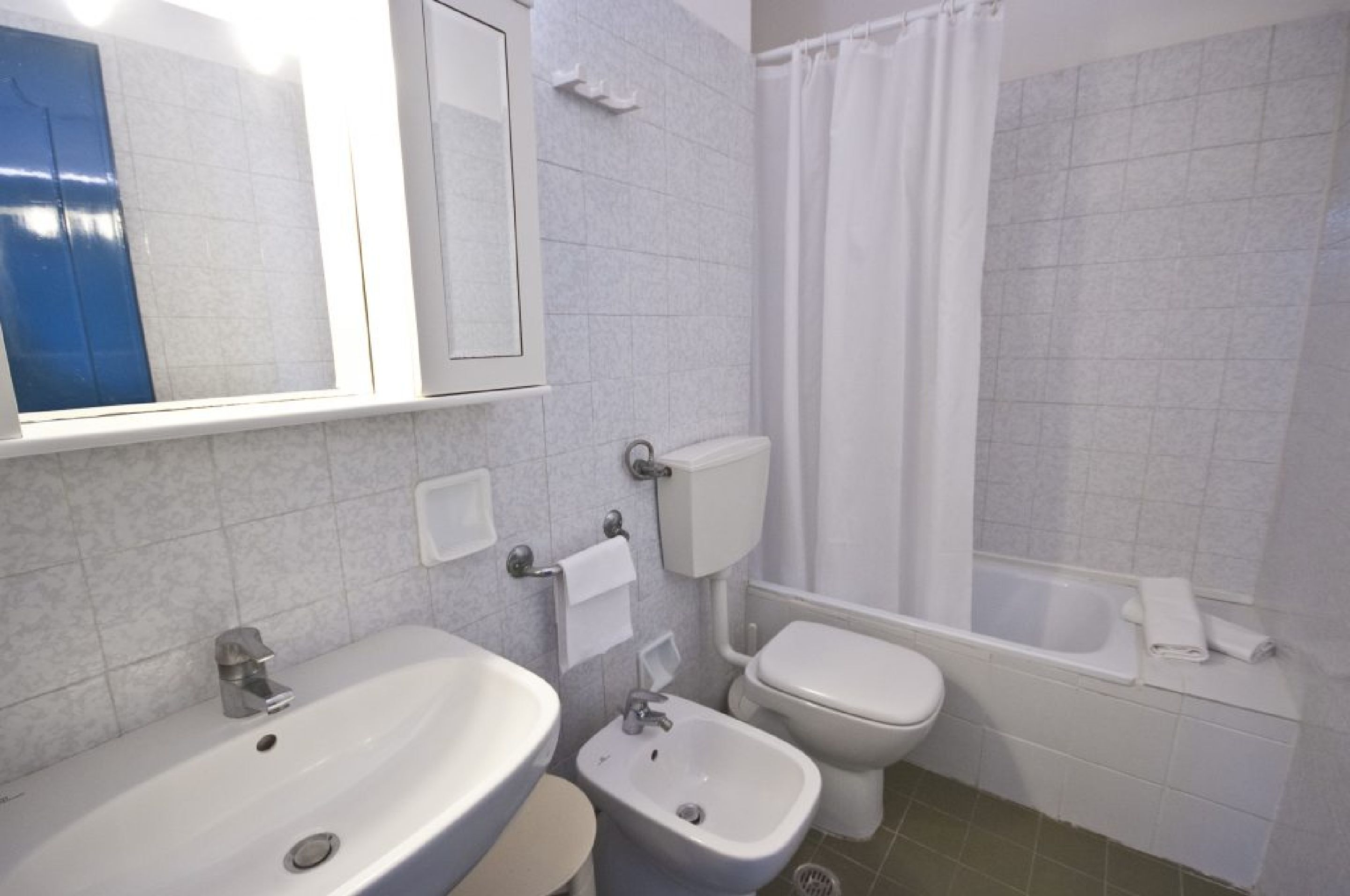 A bathroom with a sink, bidet, toilet, and bathtub.
