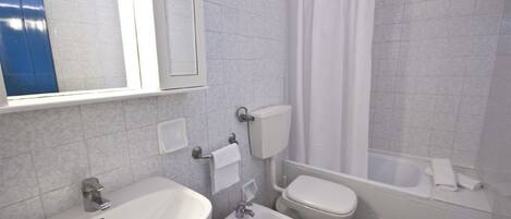 A bathroom with a sink, bidet, toilet, and bathtub.