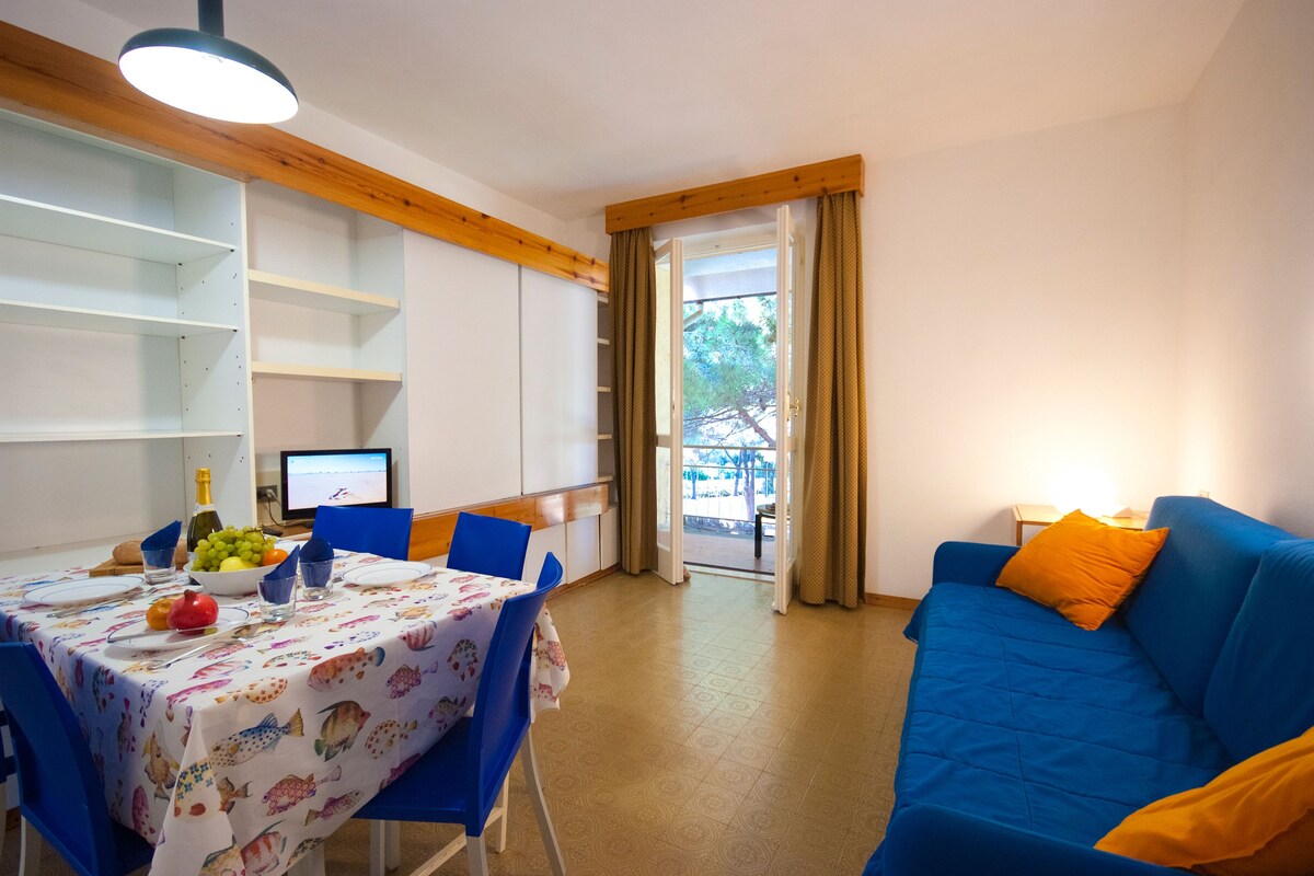 A dining area with a table set for four, a blue sofa, and a view of the outdoors.