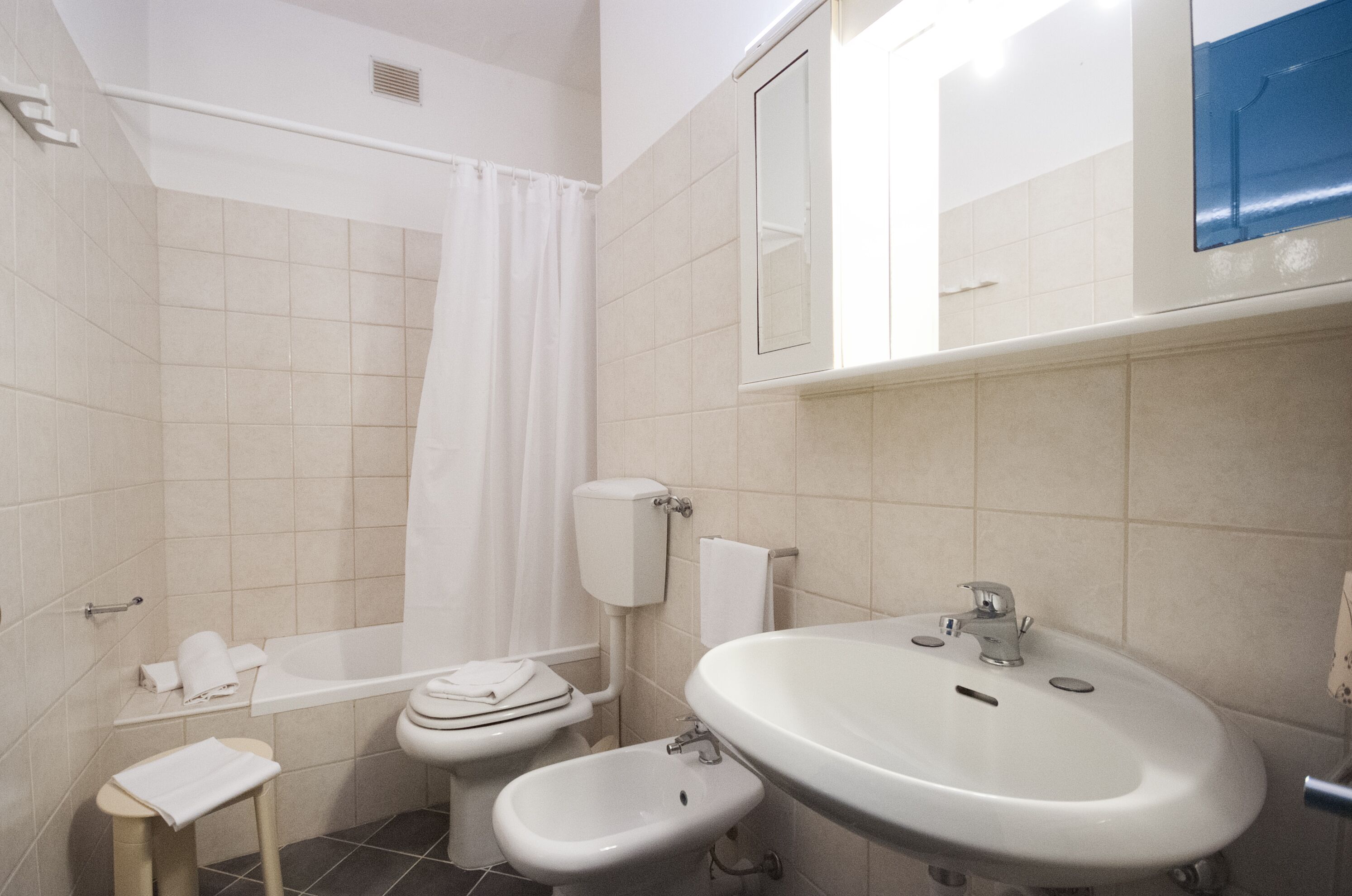 Un baño con inodoro, bidé, lavamanos y cortina de ducha.