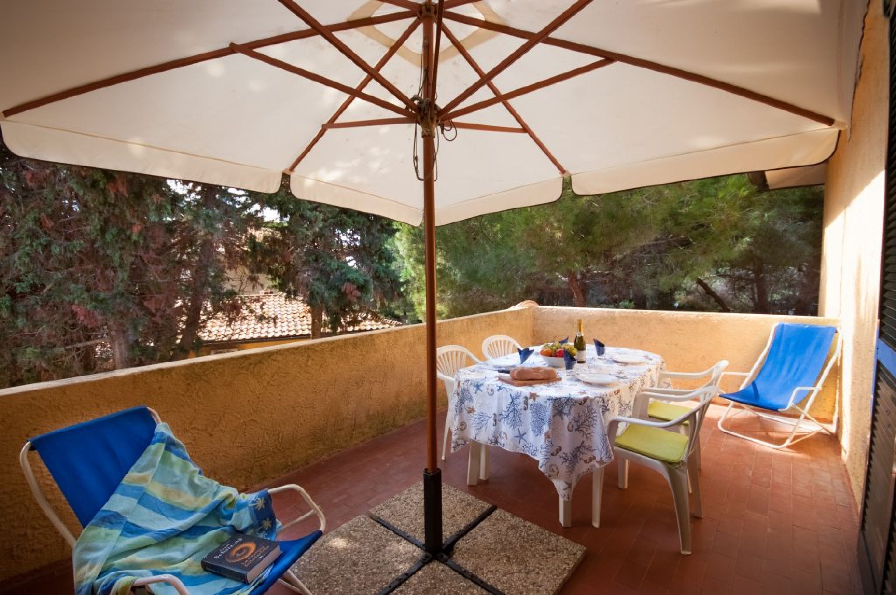 Een balkon met een tafel, stoelen en een grote parasol.