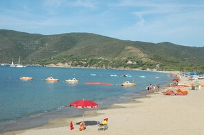 Enjoy a serene beach experience with breathtaking views of the calm sea and surrounding hills.