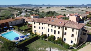 A large building with a swimming pool, multiple balconies, and a view of the surrounding countryside. - Residence Giuly Rosselmini (Santa Luce)