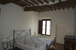 A bedroom with a bed, a nightstand, a lamp, a window, and a wooden cabinet. - Residence Giuly Rosselmini (Santa Luce)