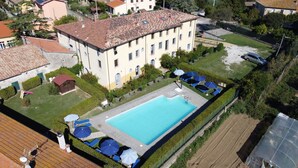Ovenfra set boligkompleks med swimmingpool, omgivet af grøn bevoksning og enkelte parkerede biler.