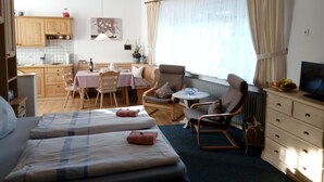 Een gezellige kamer met een bed, een eettafel, een stoel, een bank, een televisie en een raam met gordijnen.
