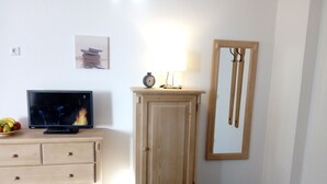 Een kamer met een houten kast, een televisie, een klok en een spiegel aan de muur.