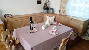 Een eethoek met een tafel gedekt voor twee personen, inclusief een fles wijn, een glas en een theeset.