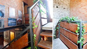 Un escalier avec une rampe en métal et des marches en bois, entouré de murs en briques et agrémenté d’œuvres d’art.