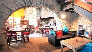 Un intérieur chaleureux avec des murs en pierre, une table en bois et un canapé agrémenté de coussins colorés.