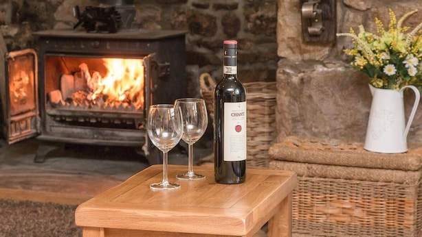 A cozy room with a stone fireplace, a bottle of Chianti wine, and two glasses on a wooden table. - Rhiwddu Barns - Brecon Beacons National Park (Llangadog)