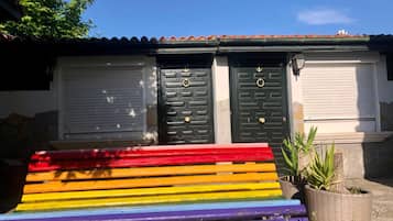 A colorful bench in front of a building with two doors and a closed window.