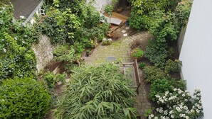 A rooftop garden with various potted plants, a wooden bench, and a small reading area. - Hotel Stern (Düsseldorf)