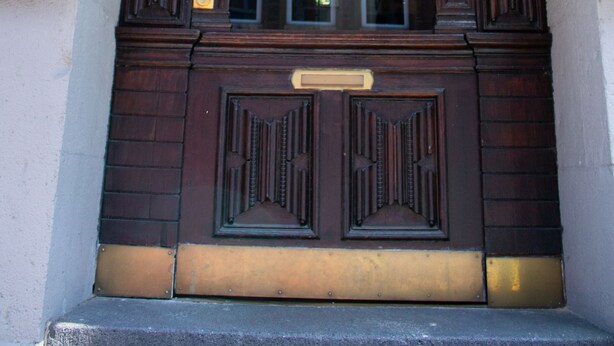 A grand entrance with ornate woodwork and a blue sign indicating a public space. - Hotel Stern (Düsseldorf)