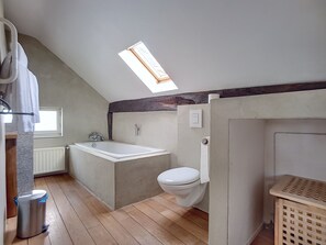 A small, compact bathroom with a skylight, a bathtub, a toilet, and a wooden floor. - Auberge du Sabotier (Saint-Hubert)