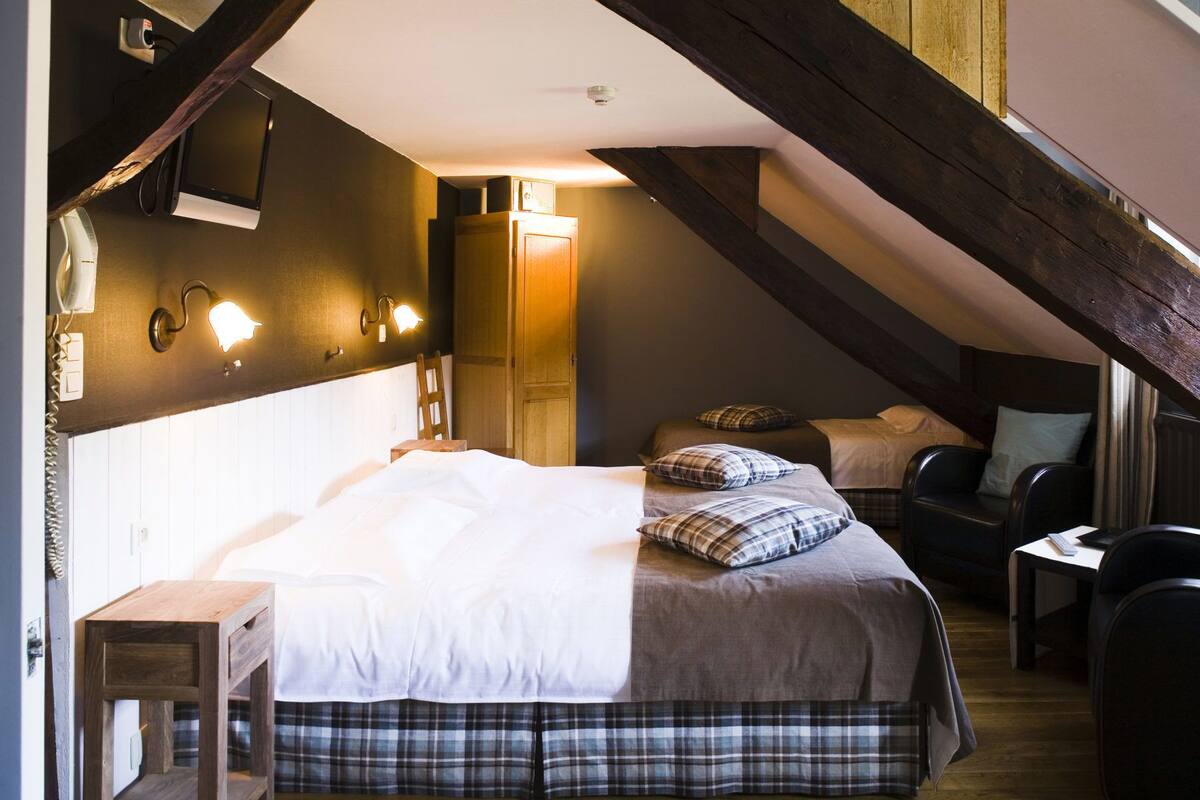 A cozy attic bedroom with a bed, a desk, and a chair.