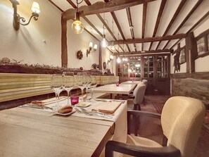 A restaurant with wooden tables and benches, lit by hanging bulbs. - Auberge du Sabotier (Saint-Hubert)