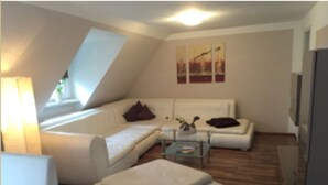 A modern living room with a sofa, ottoman, and coffee table. There is a skylight and artwork on the wall. - Pension Am Zollverein (Essen)