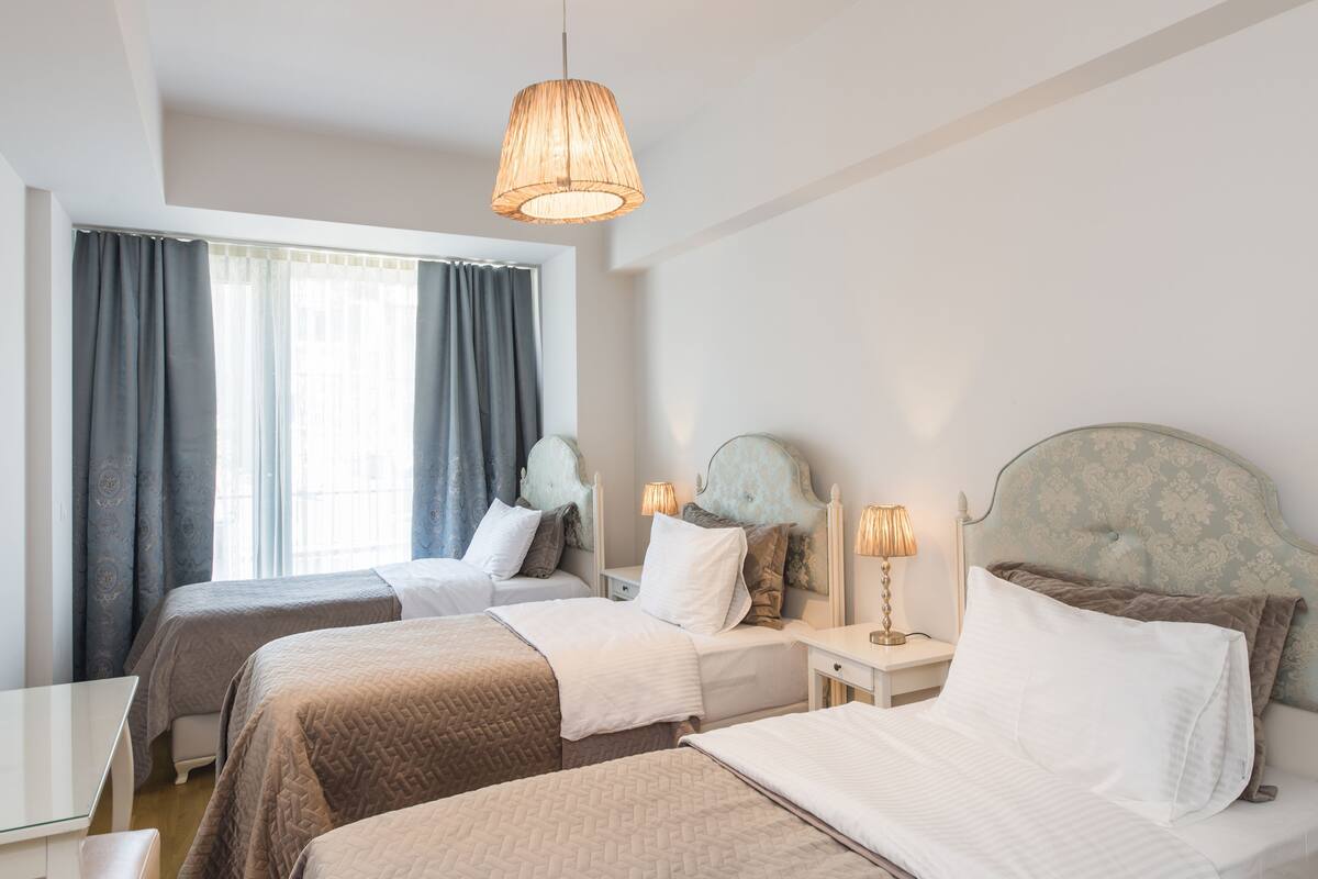 Ein Hotelzimmer mit zwei Betten, einem Schreibtisch und einem Fenster mit Vorhängen.
