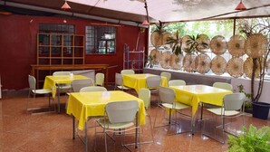 An indoor dining area with multiple tables covered with yellow tablecloths and white chairs. - Hôtel Saint-Jean (Cotonou)