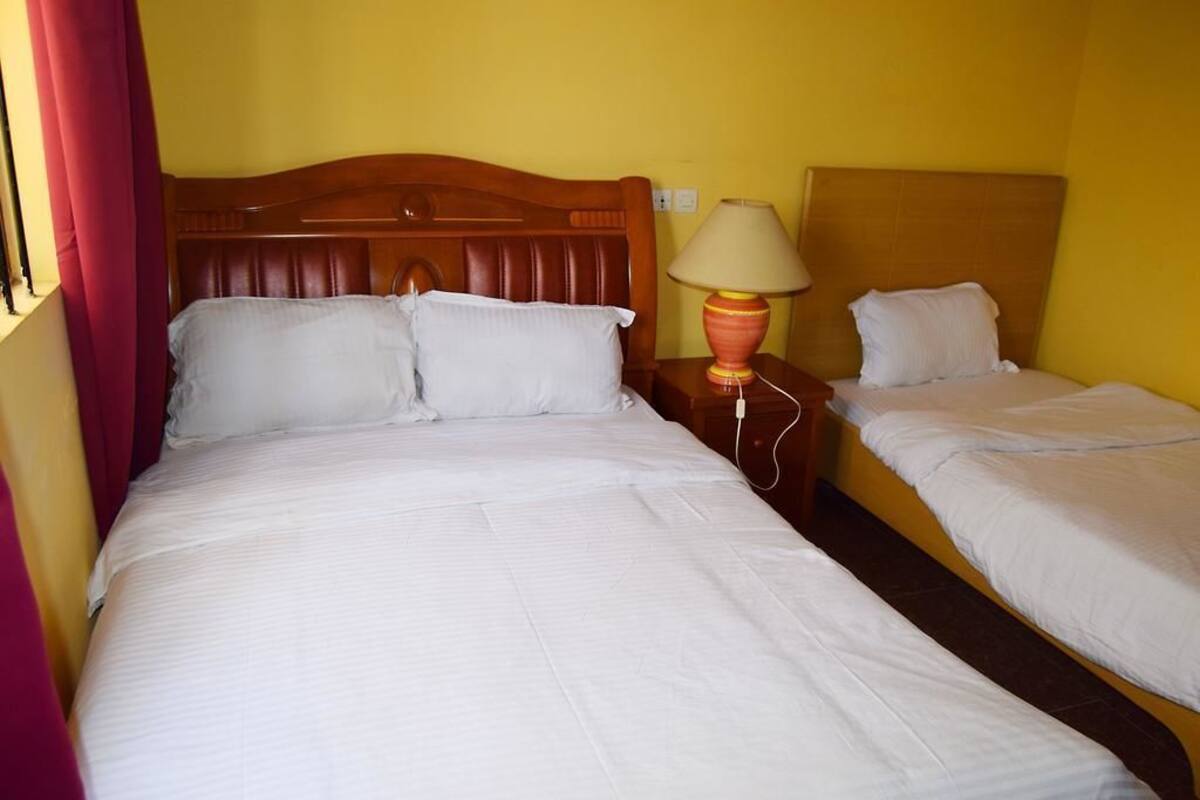 A hotel room with a large bed, a smaller bed, and a nightstand with a lamp.