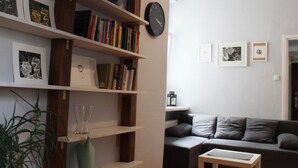 A living room with a bookshelf, a clock, and a couch. - Noctis Apartment Chmielna (Warsaw)