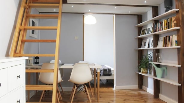 A room with a wooden ladder, a desk with chairs, a bookshelf, and a hanging light fixture. - Noctis Apartment Chmielna (Warsaw)